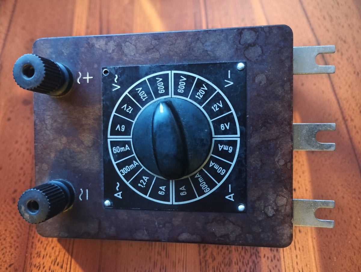 Top view of vintage brown Bakelite range selector with rotary knob, two terminal sockets and three metal contacts
