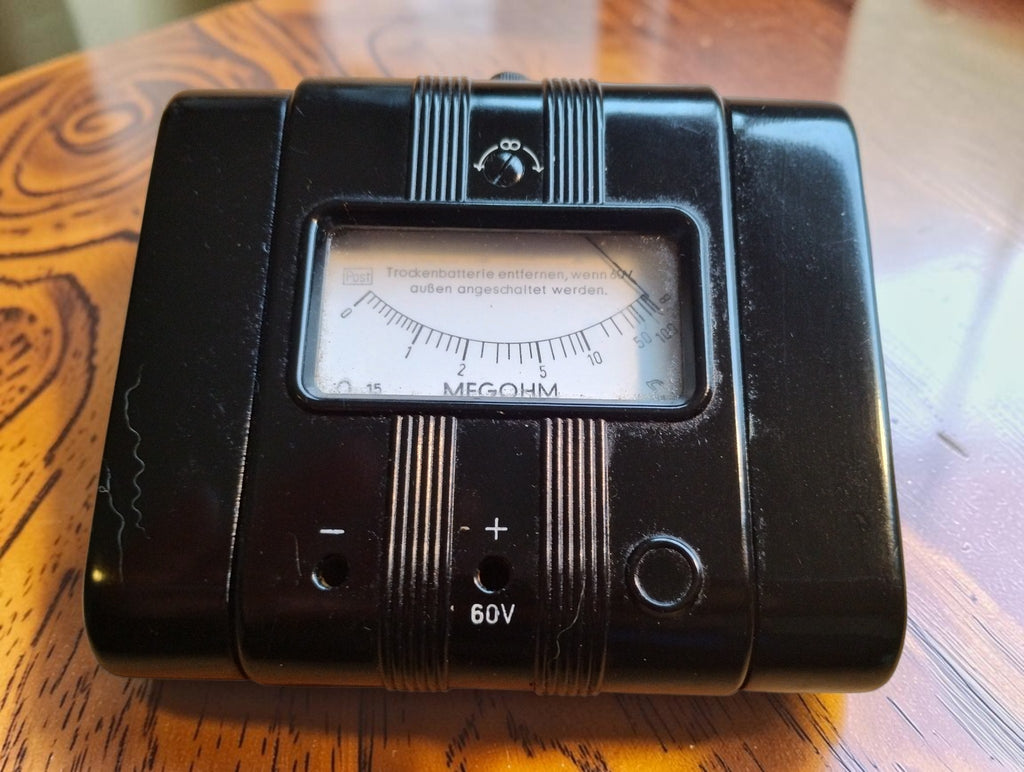 Gossen Megohm 60 V vintage insulation resistance meter with a glossy black Bakelite case and analog dial
