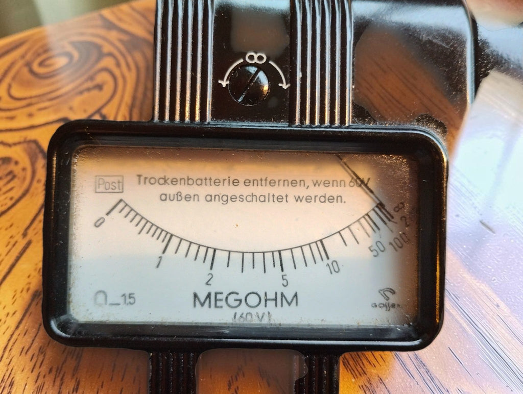 Close-up of the Gossen megohmmeter dial showing the megohm scale, Post marking and German instructions
