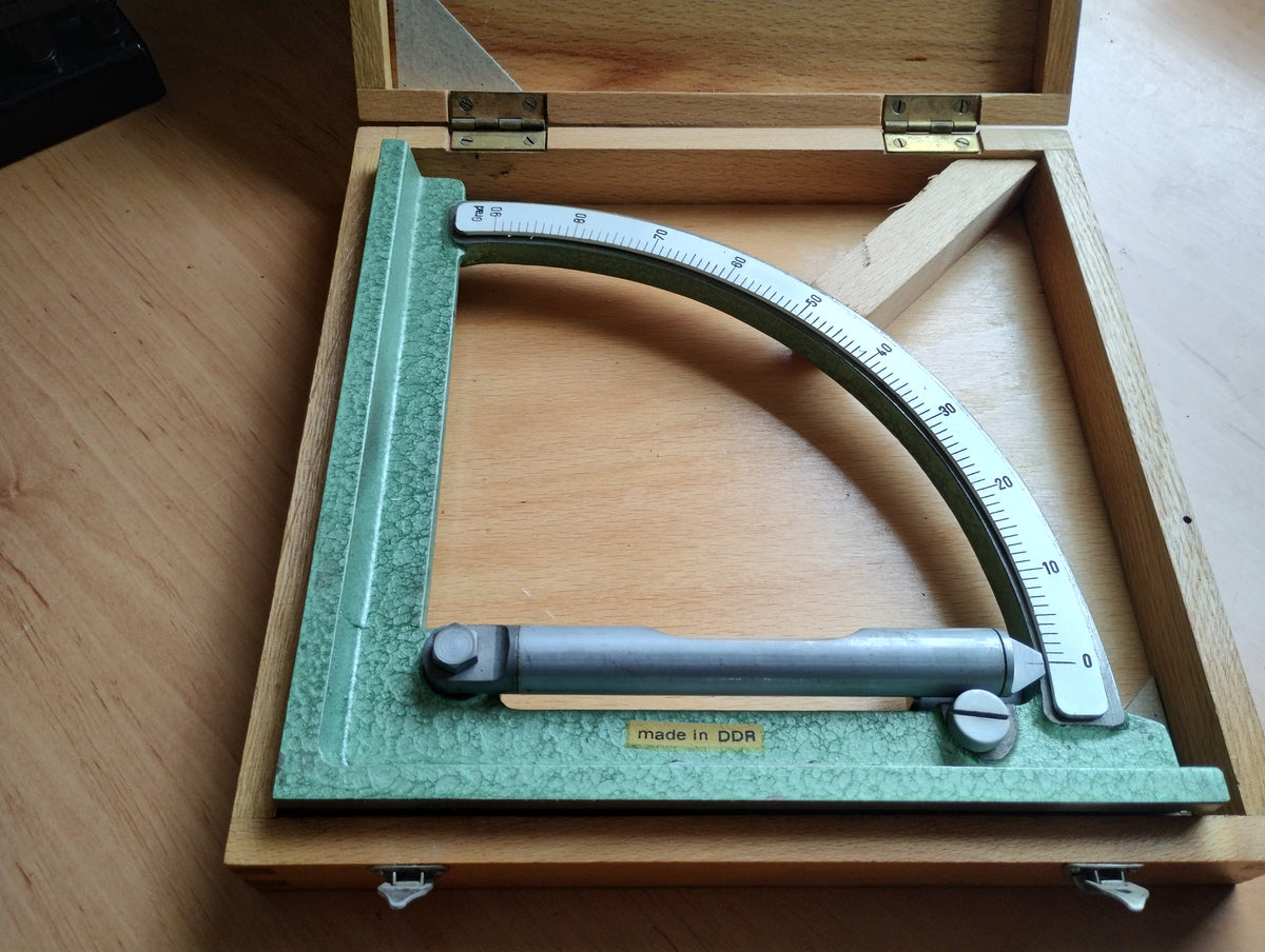 Vintage DDR mechanical inclinometer with green hammer-finish frame and 0–90 degree scale in its fitted wooden case
