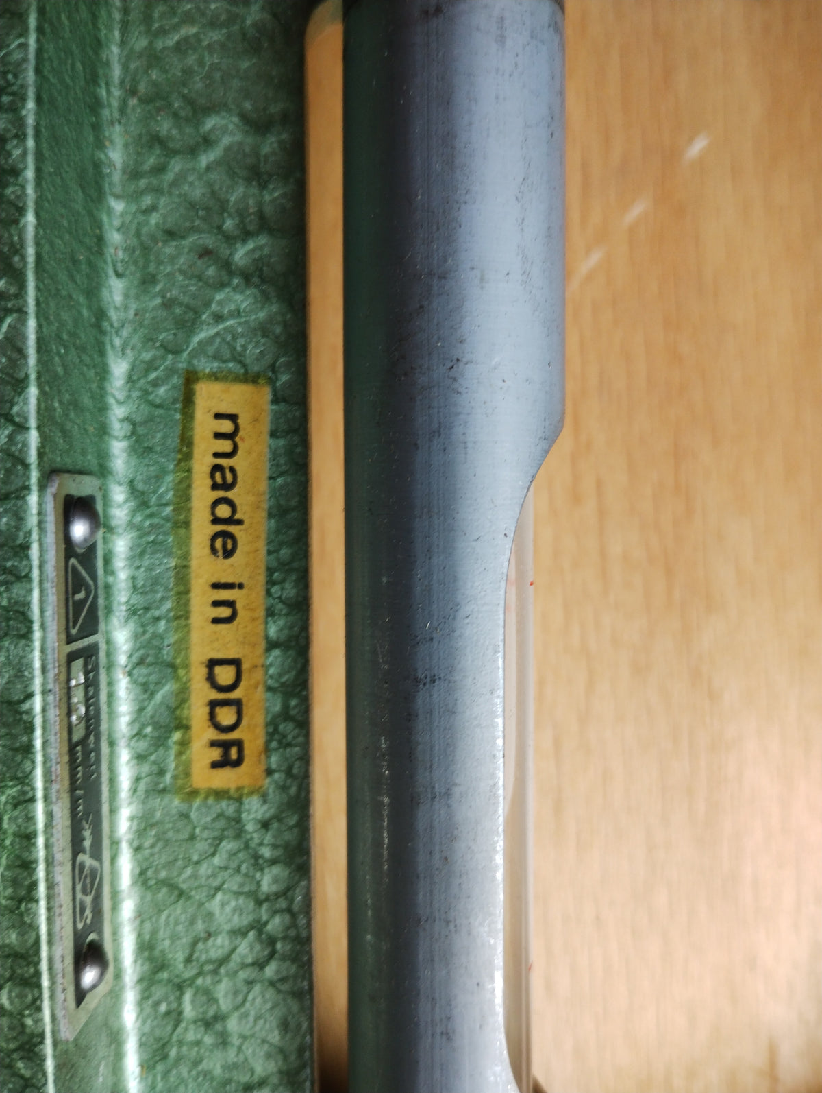 Close-up of the made in DDR label and metal spirit level housing on the green inclinometer frame
