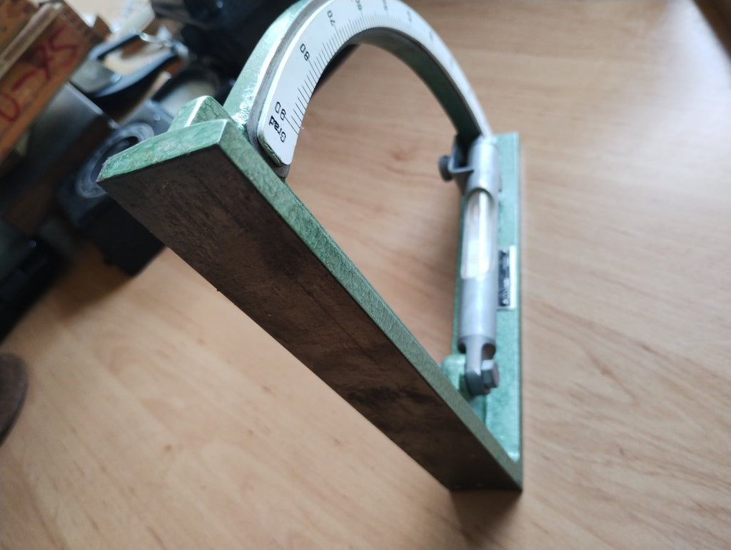 Side view of the vintage DDR inclinometer showing its metal measuring surface and curved degree scale
