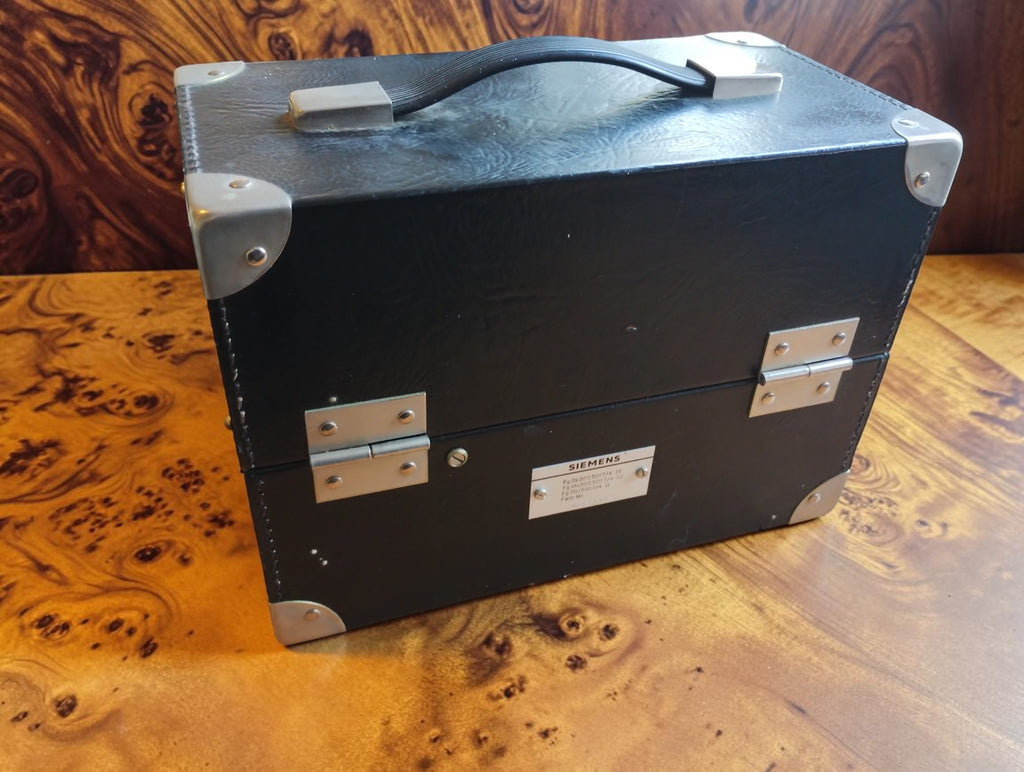 Rear view of the closed Siemens carrying case with metal hinges, reinforced corners, handle and identification plate.
