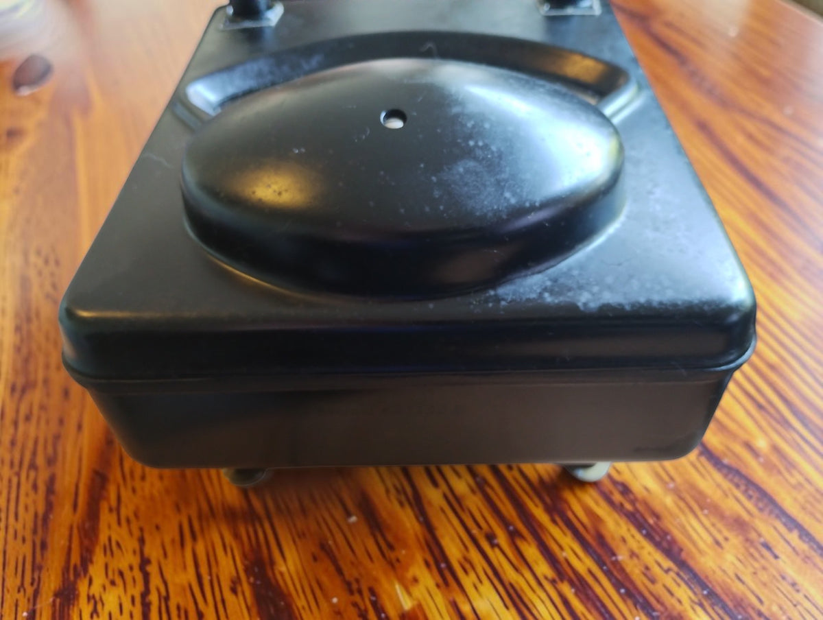 Low-angle view of the Siemens & Halske microammeter showing the raised black cover and Bakelite case with signs of age.
