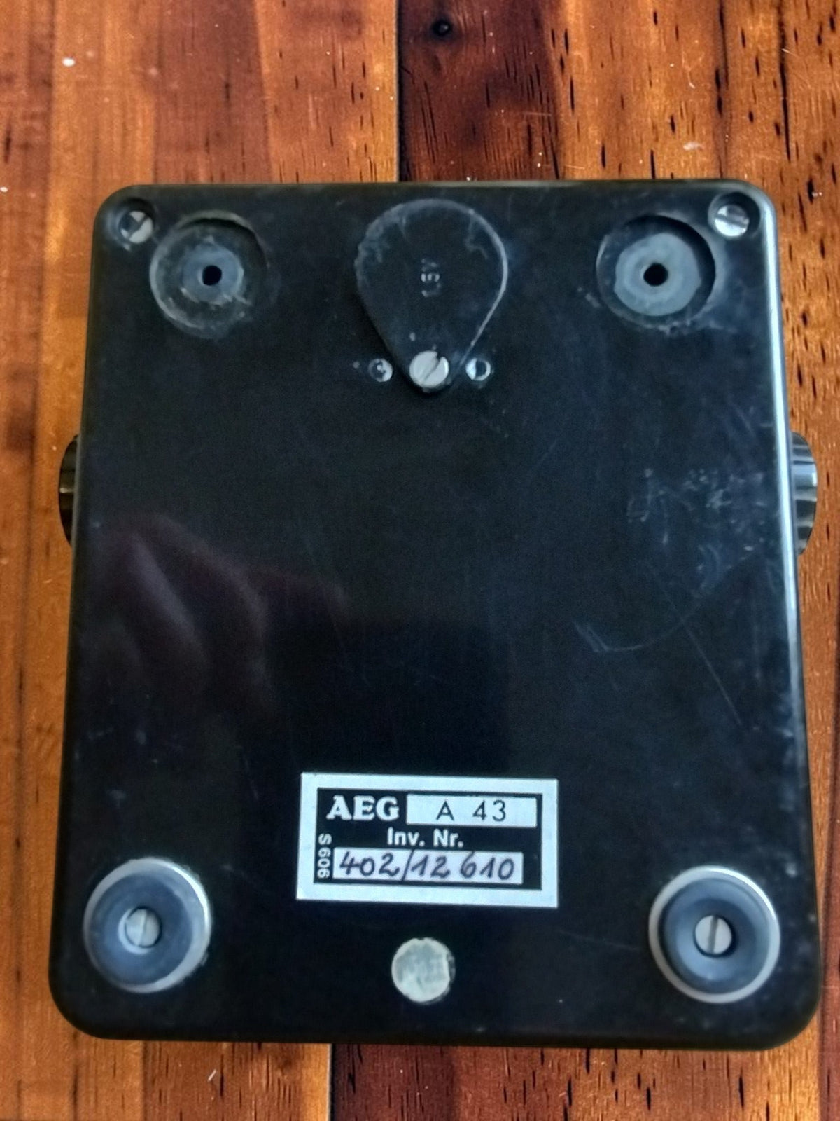 Underside of the black Bakelite insulation tester with AEG A 43 inventory label, Inv. Nr. 402/12 610, and visible wear
