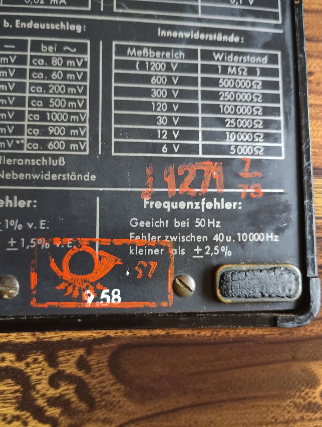 Close-up of red inspection markings and printed resistance and frequency tables on the Gossen UVA multimeter.
