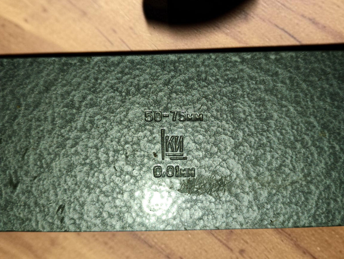Close-up of the green wooden micrometer case showing the 50–75 mm range, 0.01 mm graduation and maker's logo.
