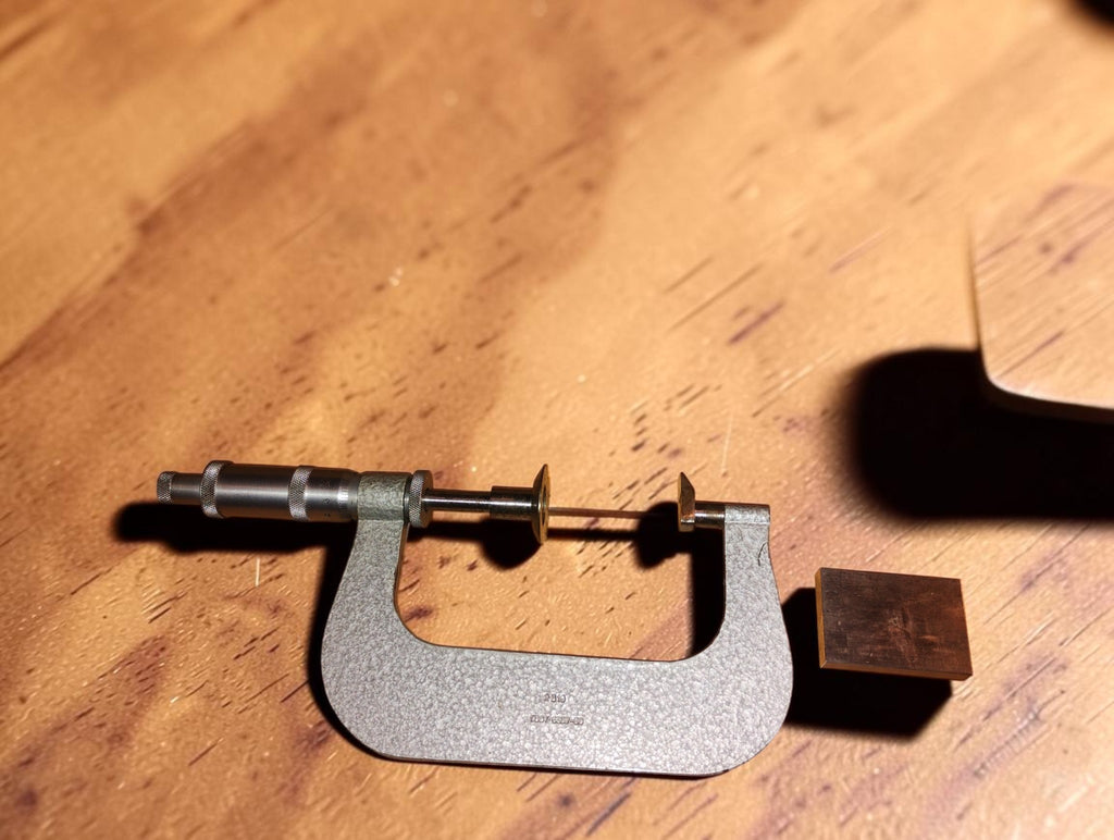 Vintage Soviet disc micrometer with broad measuring faces and hammered finish, shown beside its wooden case.
