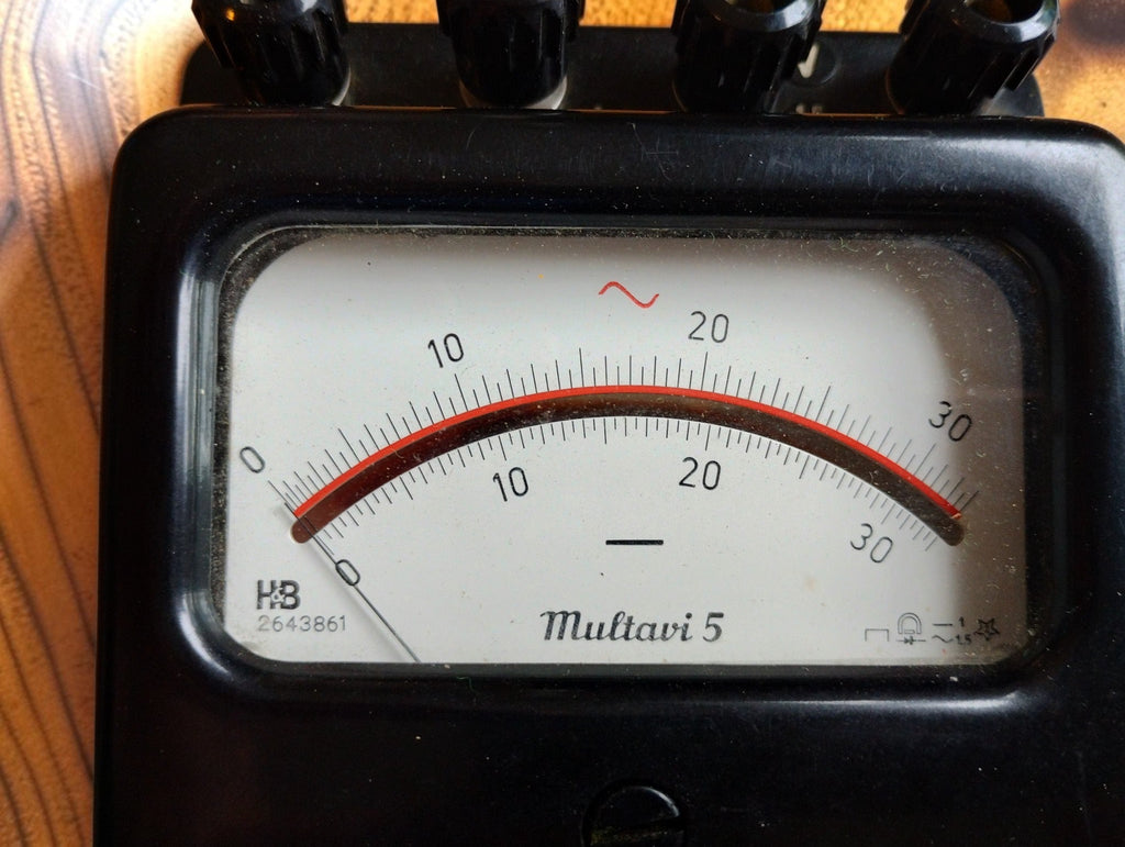 Close-up of the cream-colored dial of the Hartmann & Braun Multavi 5 analog multimeter with red pointer and black bakelite housing
