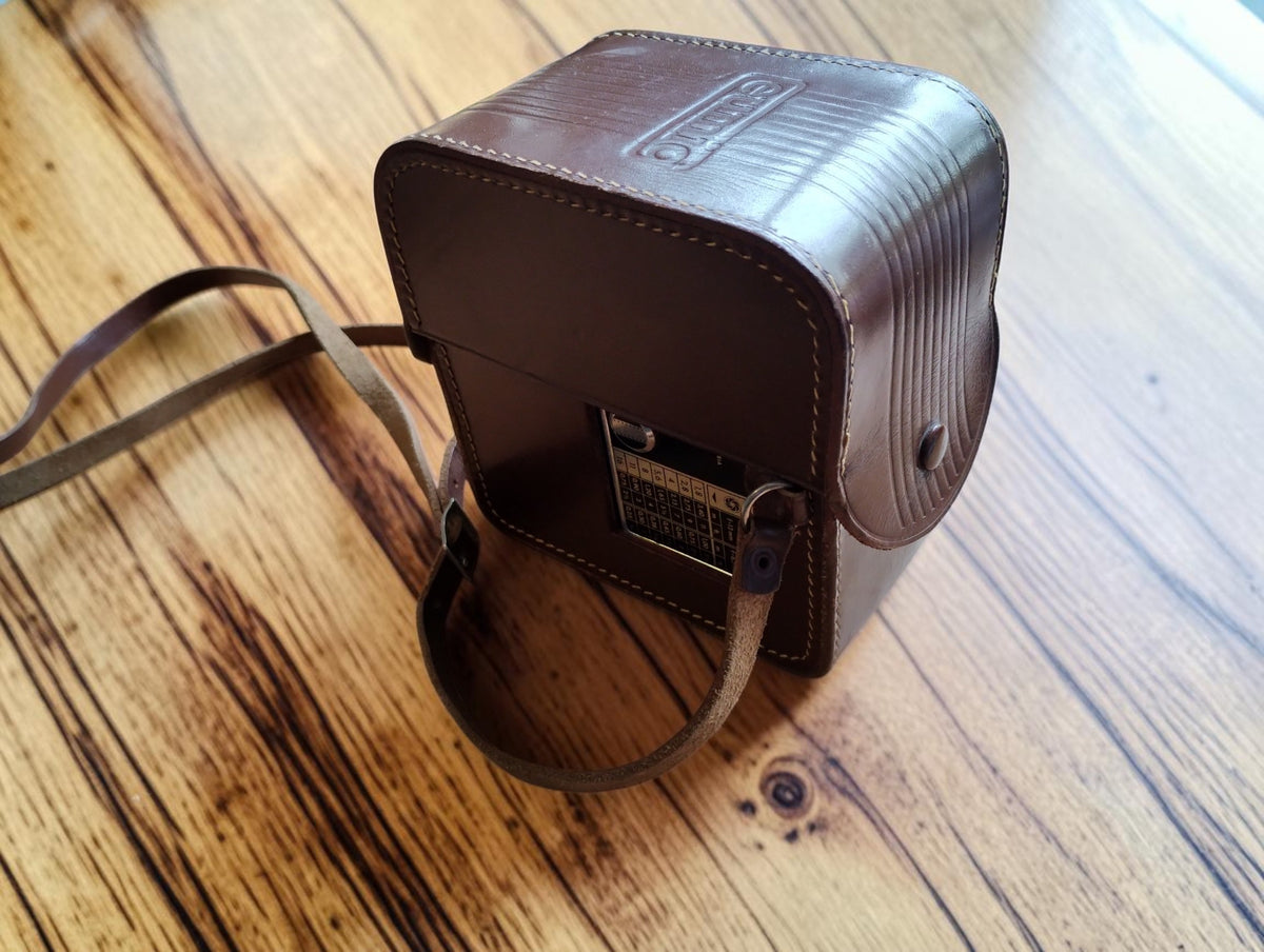Angled view of the Eumig leather carrying case with embossed logo, stitching and shoulder strap

