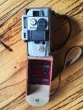 Eumig Servomatic 8mm movie camera in its open brown leather carrying case with accessories inside the lid
