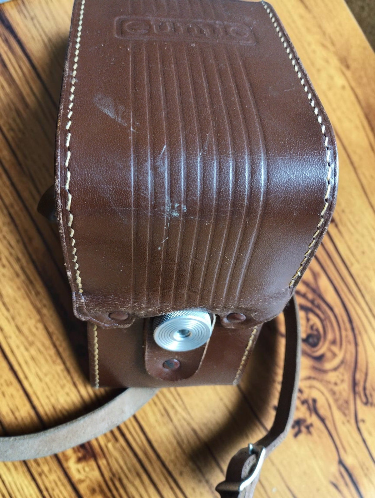 Brown leather Eumig camera case with metal fastening, shoulder strap and visible wear
