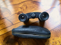 Vintage Aida 2.5 × 30 opera glasses with black zippered carrying case on a wooden table
