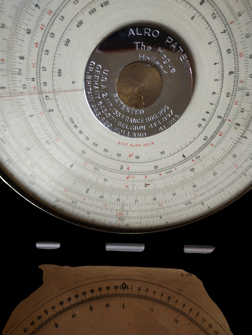 ALRO 200R circular slide rule with its metal cover open, showing the main dial and part of the reference scale inside the lid.
