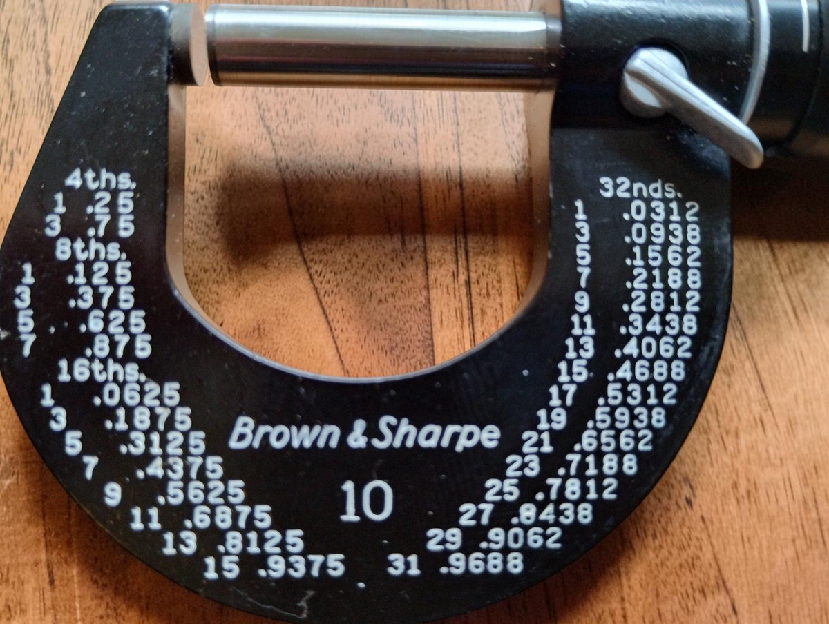 Close-up of Brown & Sharpe branding, No. 10 marking, inch conversion tables and locking lever on the micrometer
