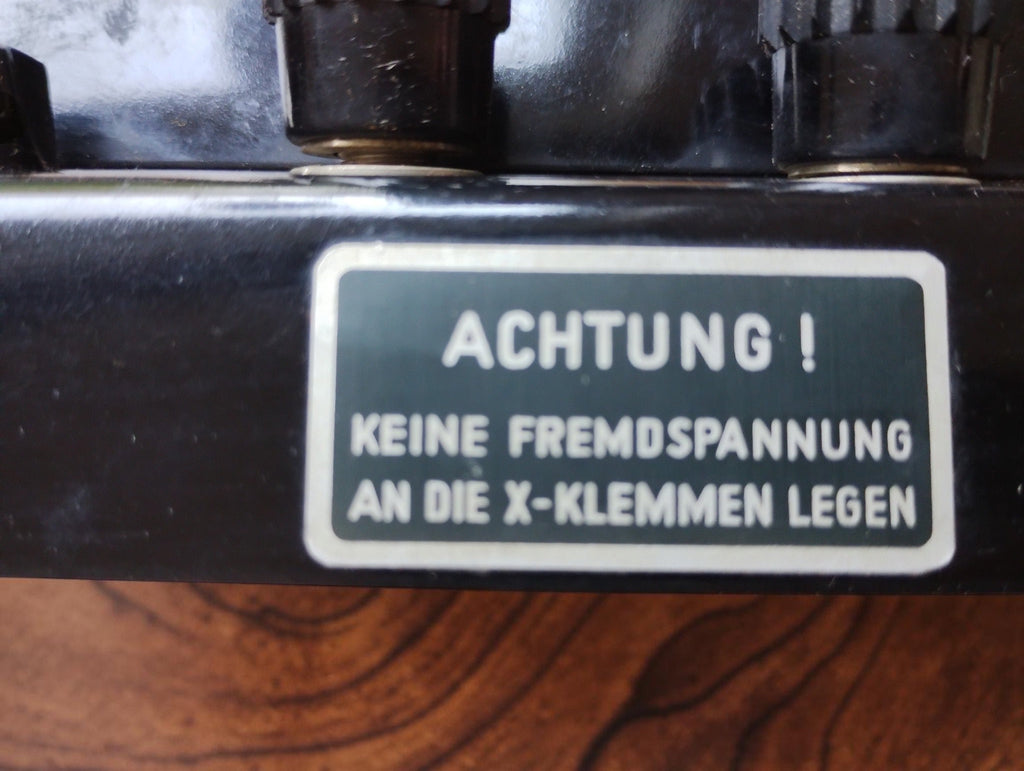 Close-up of the German warning label reading ACHTUNG! Keine Fremdspannung an die X-Klemmen legen
