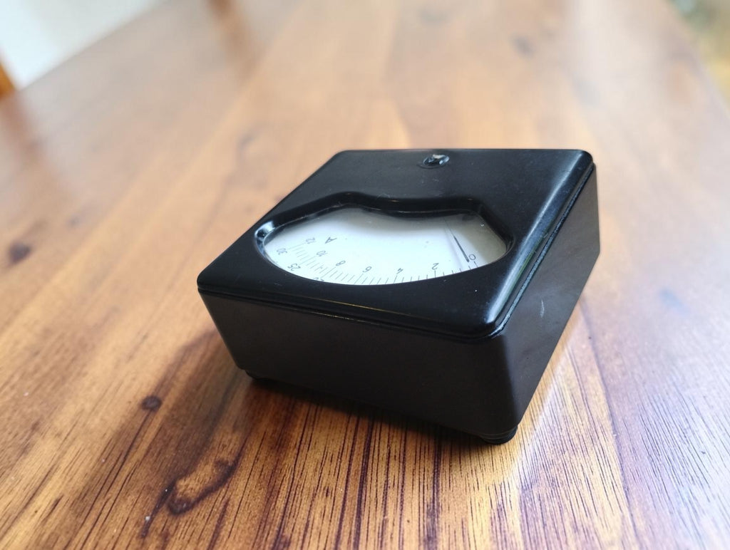 Opposite angled view of the black laboratory meter showing the dial and wear on the housing
