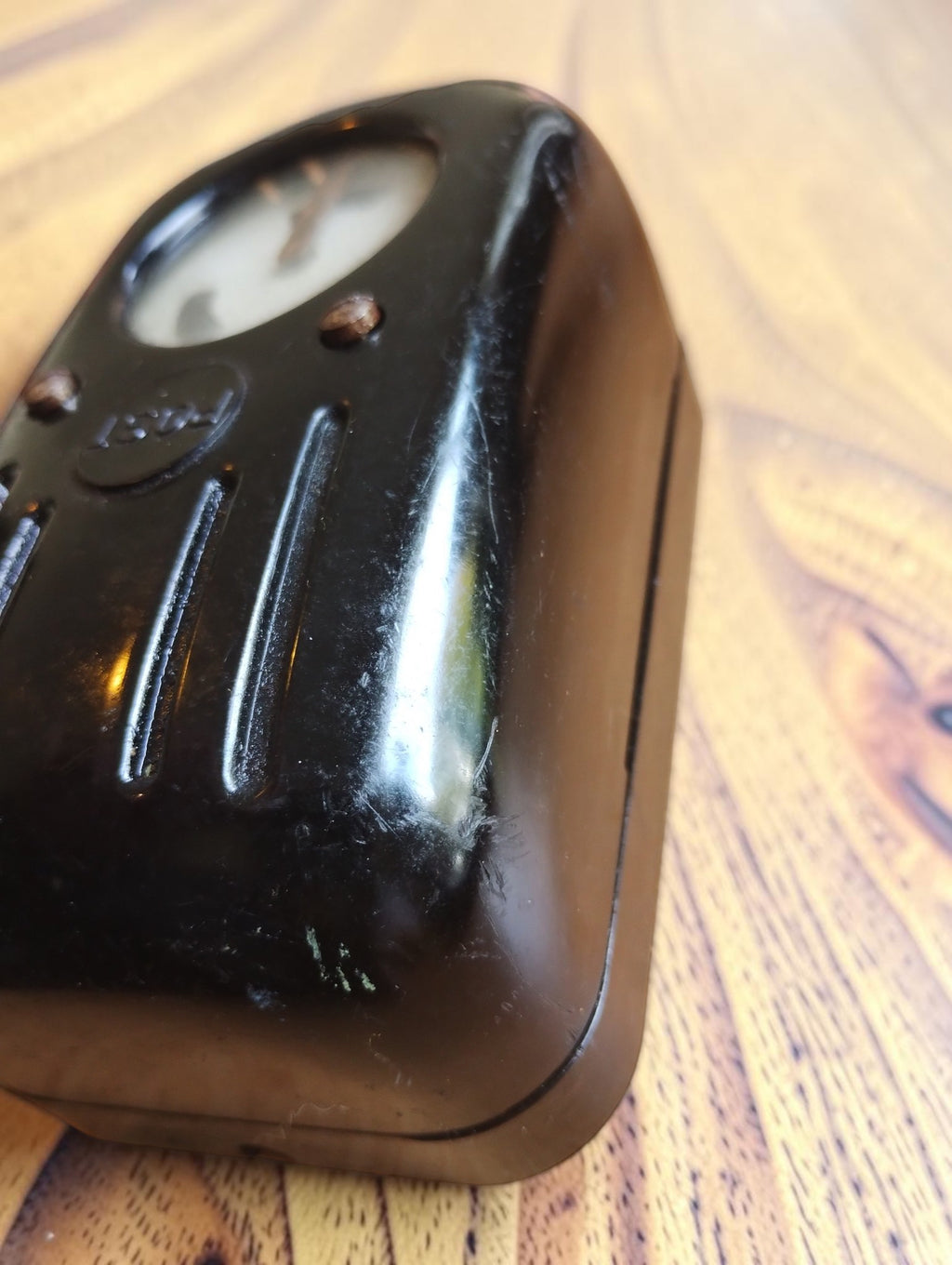 Angled side view of the vintage POST line tester showing the curved black Bakelite housing and casing seam.
