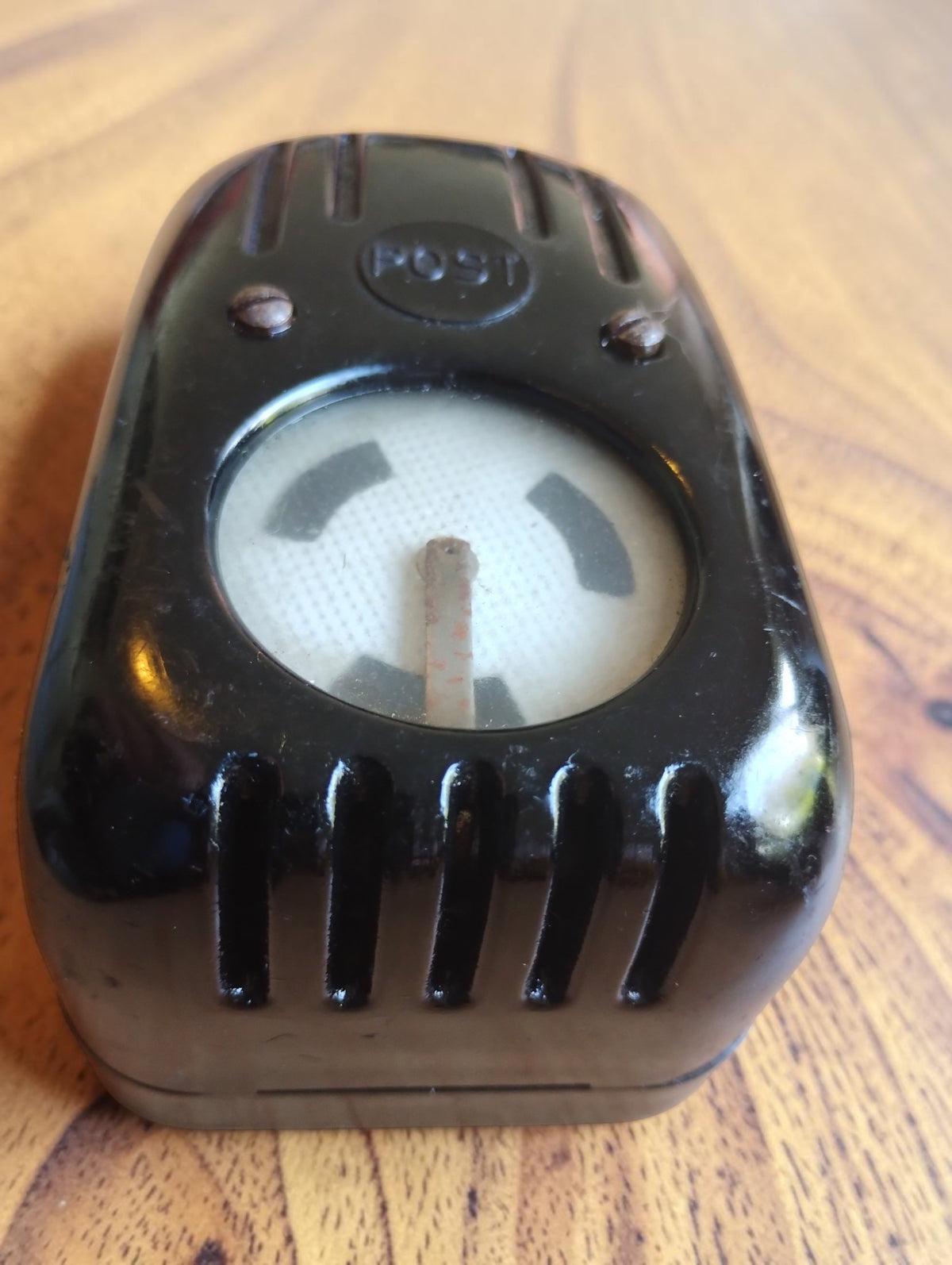 Vintage POST line tester viewed from the opposite end, showing the indicator needle, round window and ribbed casing.
