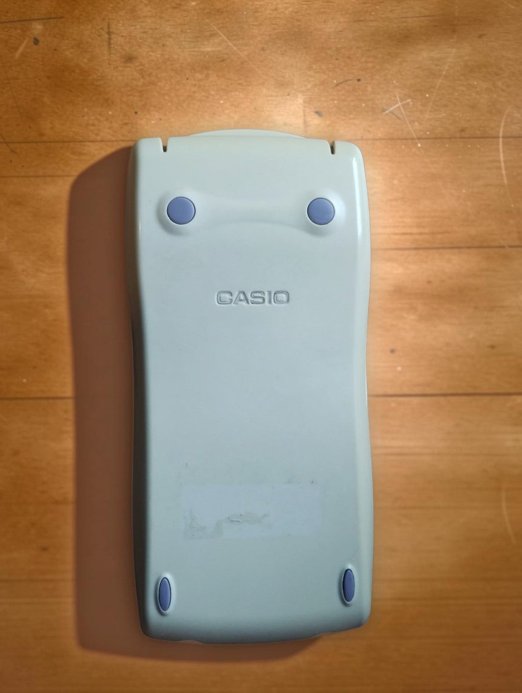 Light-colored Casio protective slide cover with four blue pads for the CFX-9850GB PLUS graphing calculator.
