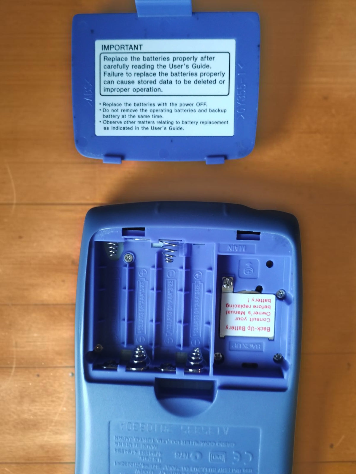 Open battery compartment of the Casio CFX-9850GB PLUS calculator with the battery cover removed.
