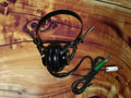 Vintage S.F. mono headphone made in Japan, with black steel headband, single black earcup, and a cord ending in green and white banana plugs.
