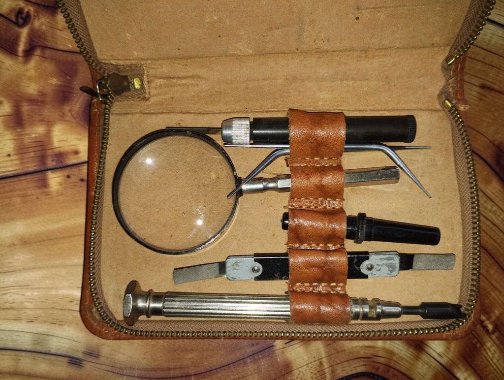Close-up of the magnifying glass and precision tools held by leather loops in the Siemens tool case
