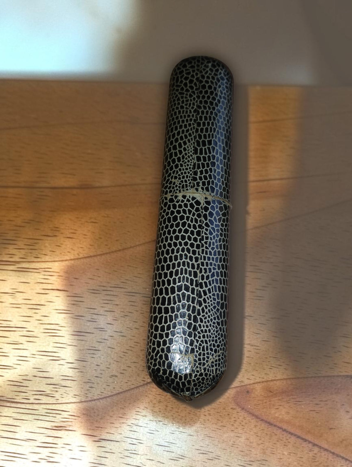 Reverse side of the vintage reptile-pattern drafting instrument case, showing wear around the join
