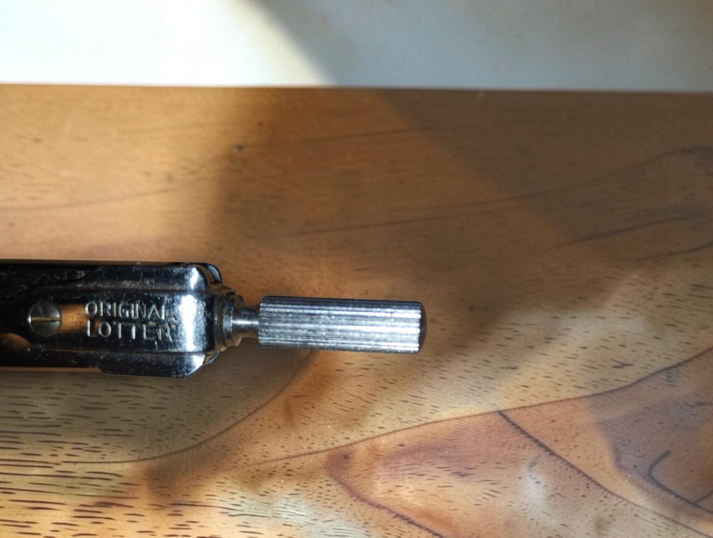 Close-up of the ORIGINAL LOTTER maker's mark and ribbed metal handle on a vintage drafting instrument
