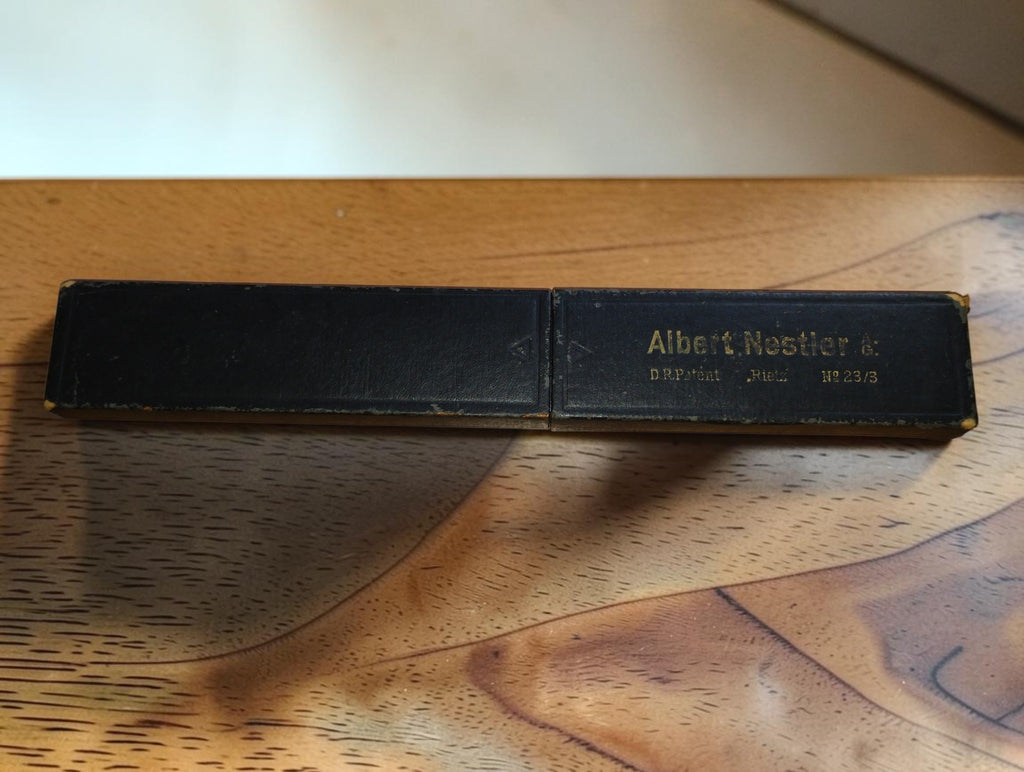 Closed black slide rule case with Albert Nestler lettering and visible wear along the edges
