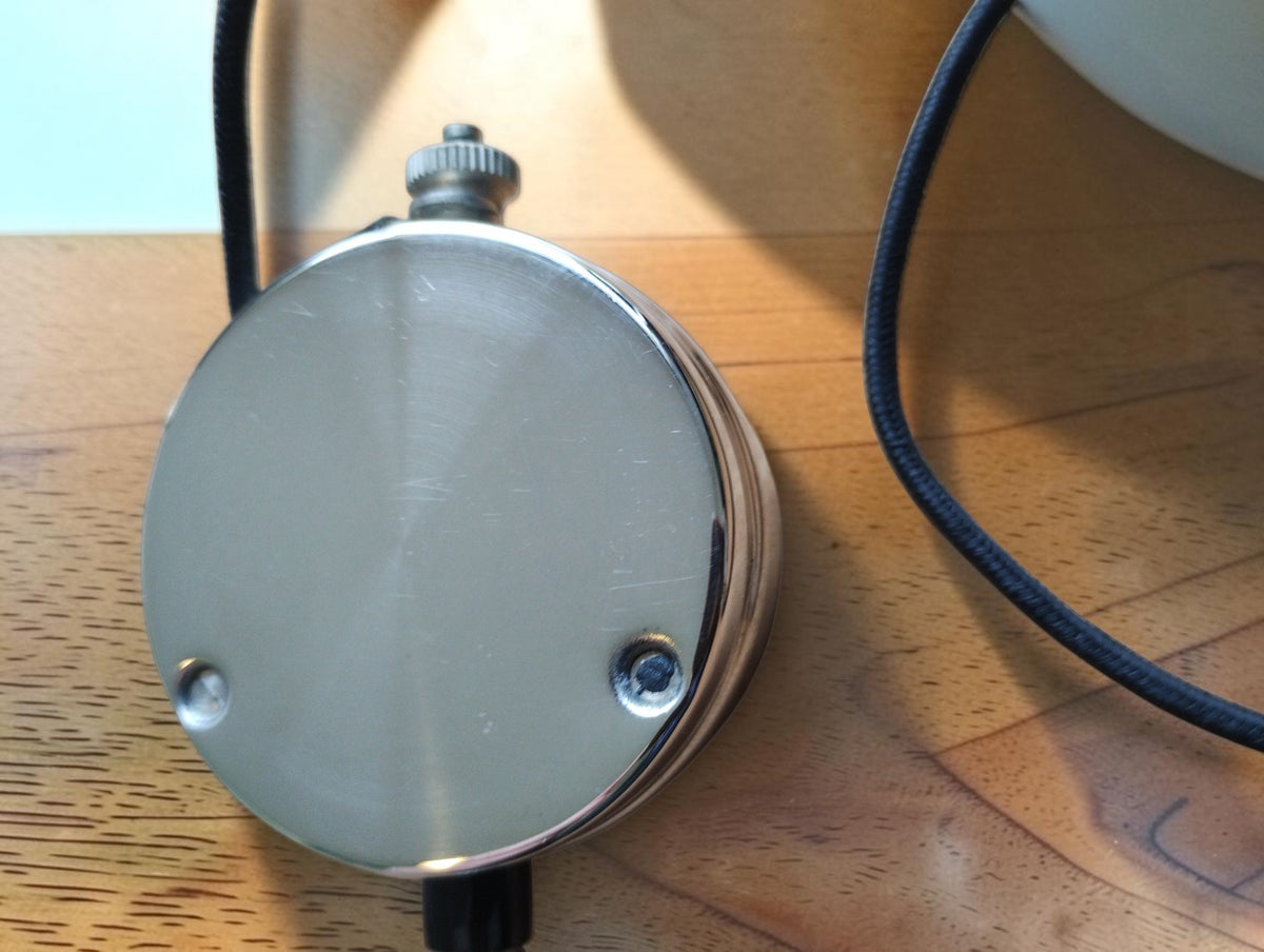 Rear view of Metrawatt TEL-38 pocket voltmeter showing the metal back plate and cloth-covered lead
