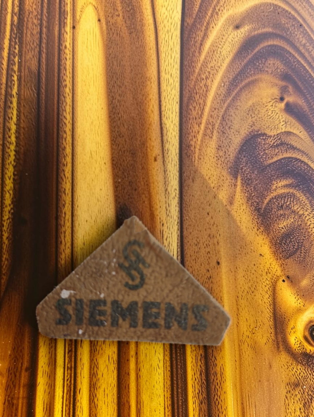 Close-up of the worn triangular paper label with Siemens lettering and logo from the vintage set's storage box.
