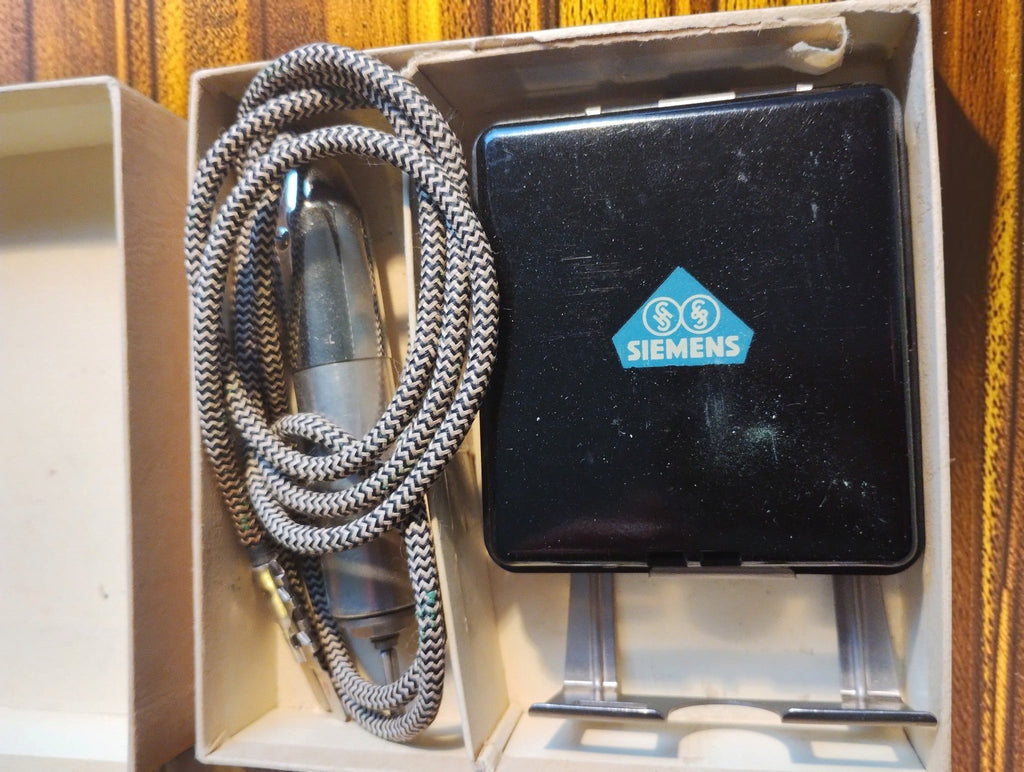 Vintage Siemens set in its open box, showing the black Bakelite unit, metal bracket, chrome probe and woven cord.
