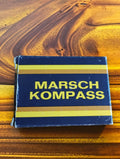 Original vintage compass box with yellow Marsch Kompass lettering on a dark blue background

