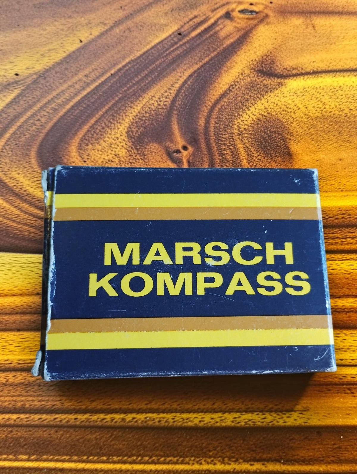 Original vintage compass box with yellow Marsch Kompass lettering on a dark blue background
