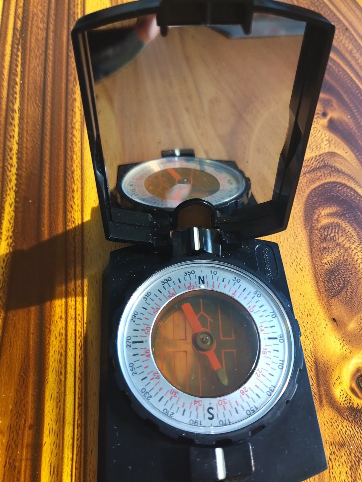 Vintage Kommit Camping compass with the mirror lid open, showing the compass dial and its reflection
