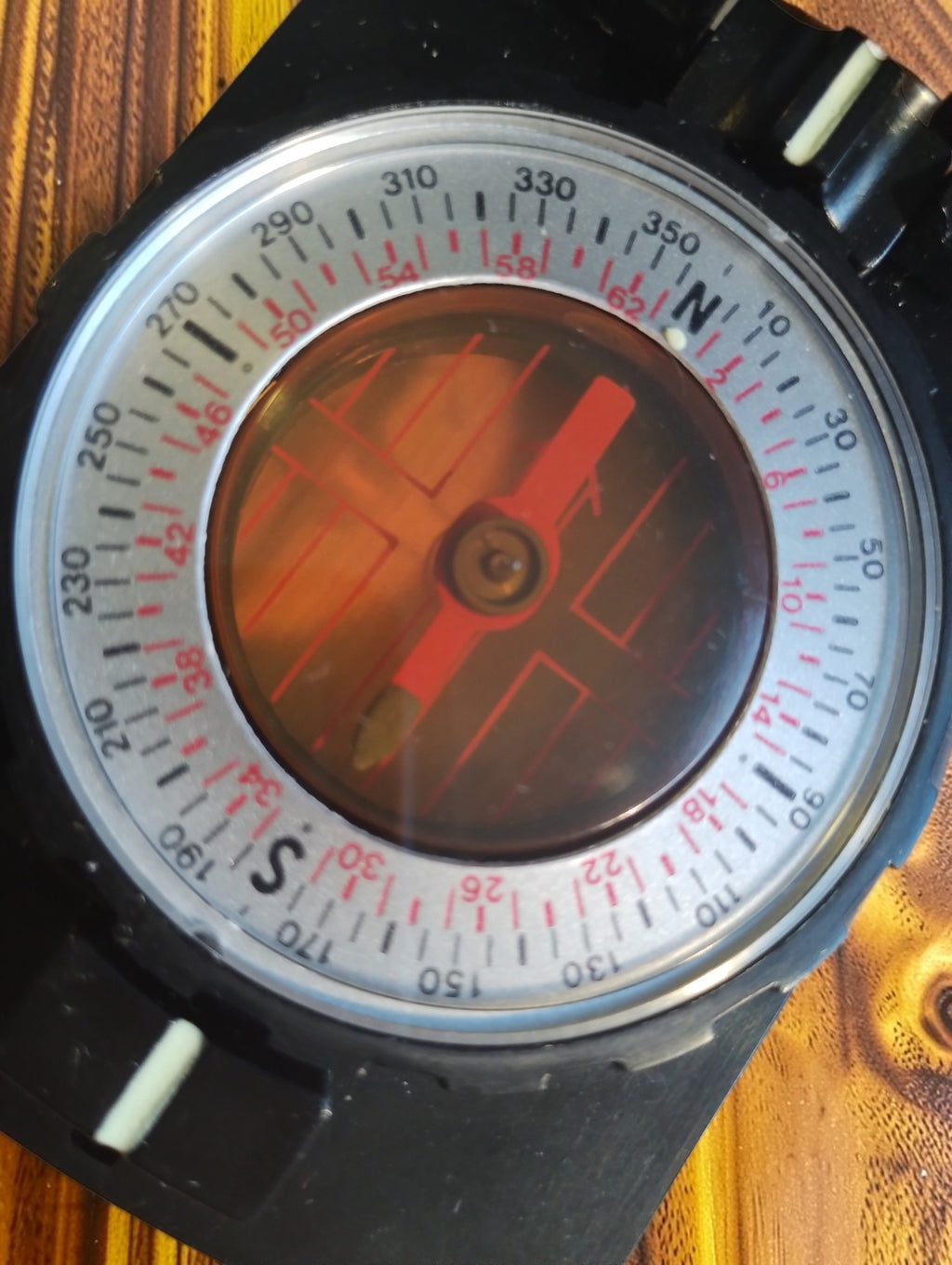 Close-up of the vintage compass dial with a red needle, degree markings and a red secondary scale
