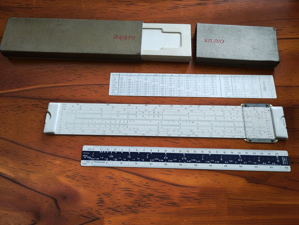 ARISTO Studio 0968 slide rule set with cursor, gray case, conversion table, and No. 1367 scale ruler.
