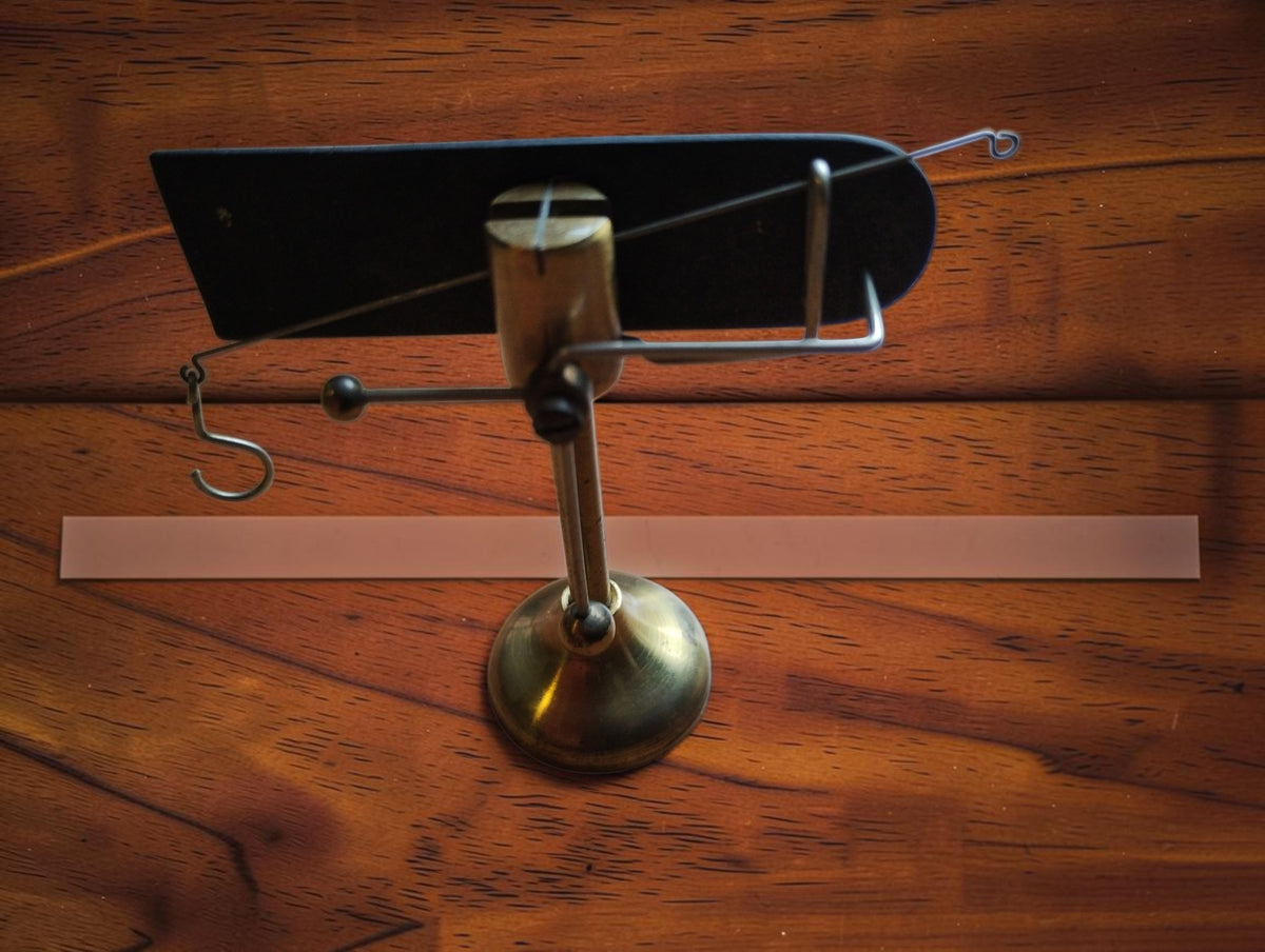 John Nesbitt brass yarn balance on its pedestal, showing the balance arm, hooks and dark backing plate.
