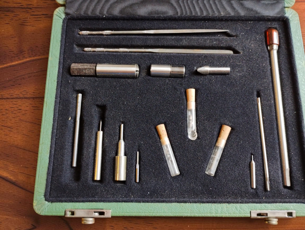 Detailed view of DIXI precision watchmaking tools, metal attachments and three cork-stoppered glass tubes in the fitted case
