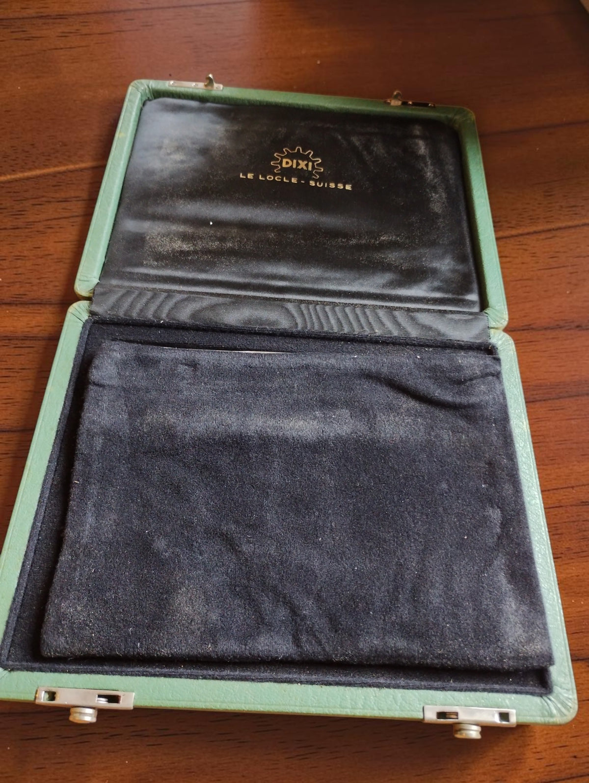 Open green DIXI Le Locle watchmaking tool case with the black protective flap covering the tools and the lid logo visible
