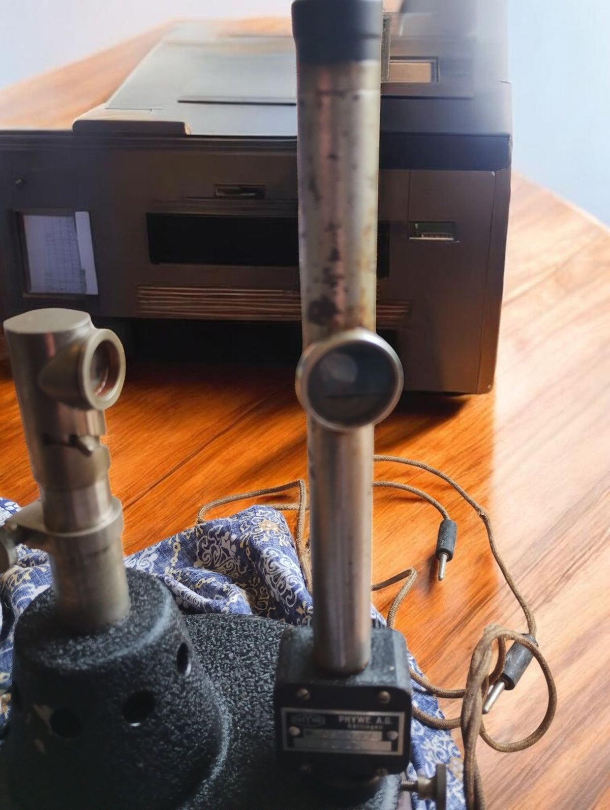 PHYWE Göttingen vintage laboratory apparatus with two metal uprights on a black textured base, showing oxidation on the taller tube.





