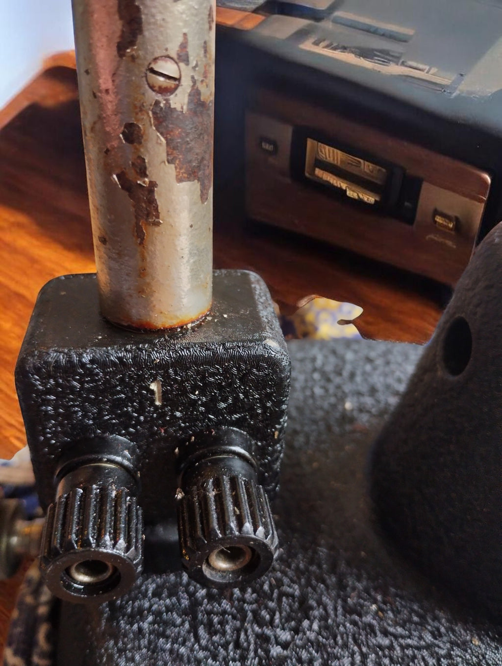 Close-up of two black electrical terminals and surface corrosion on the metal upright of the vintage PHYWE laboratory apparatus.



