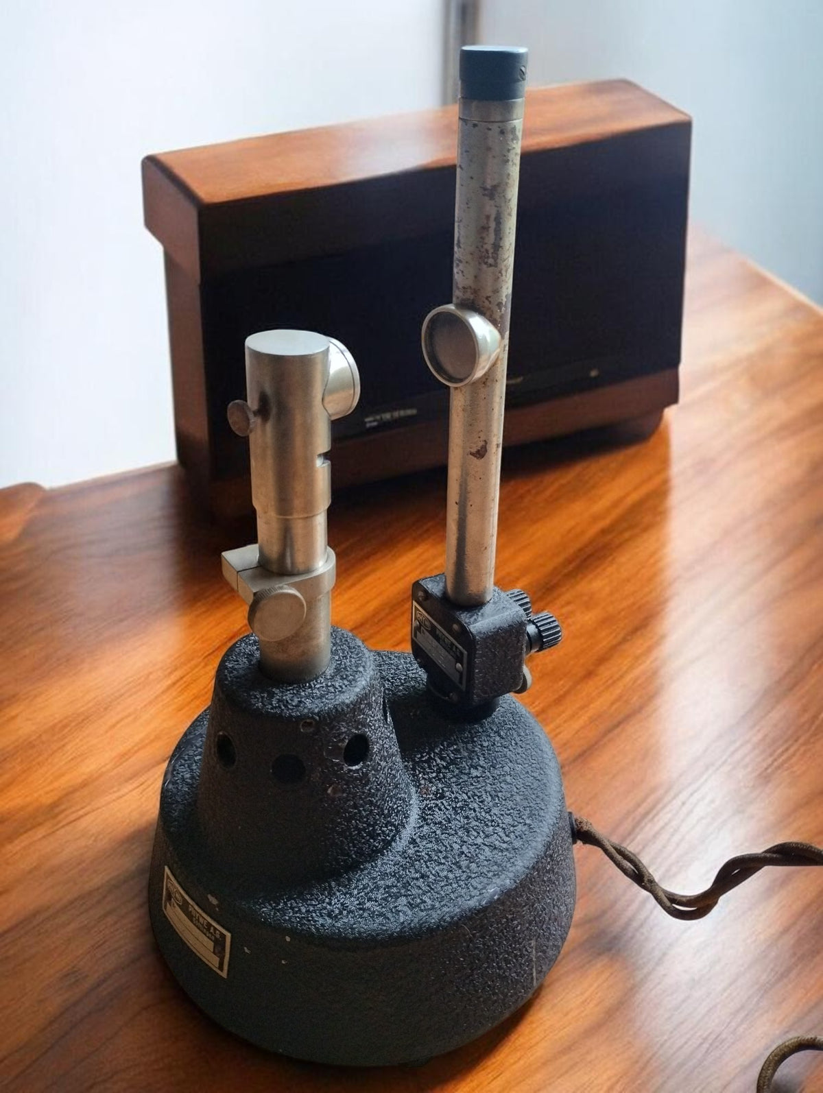 PHYWE Göttingen vintage optical laboratory ensemble with two metal uprights, a round black textured base, and a fabric-covered cable.


