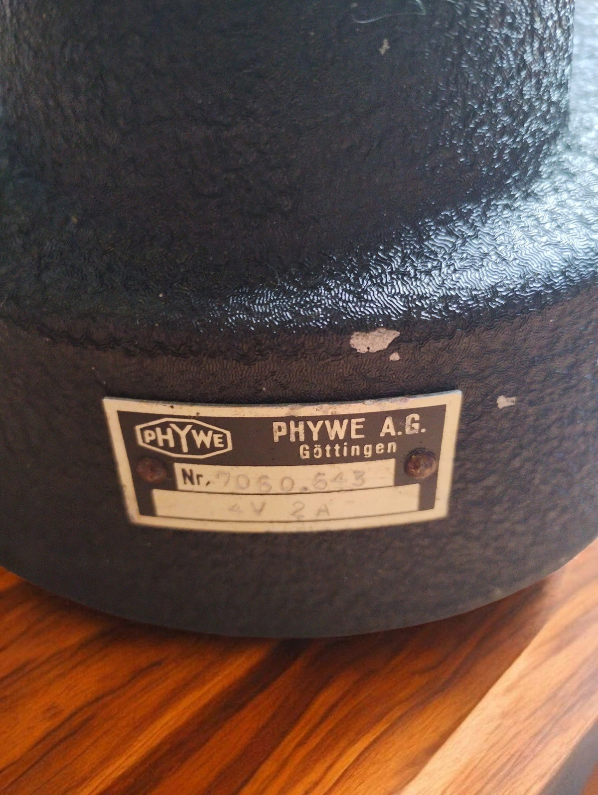 Original PHYWE A.G. Göttingen identification plate on the black laboratory base, with worn paint visible above the plate.




