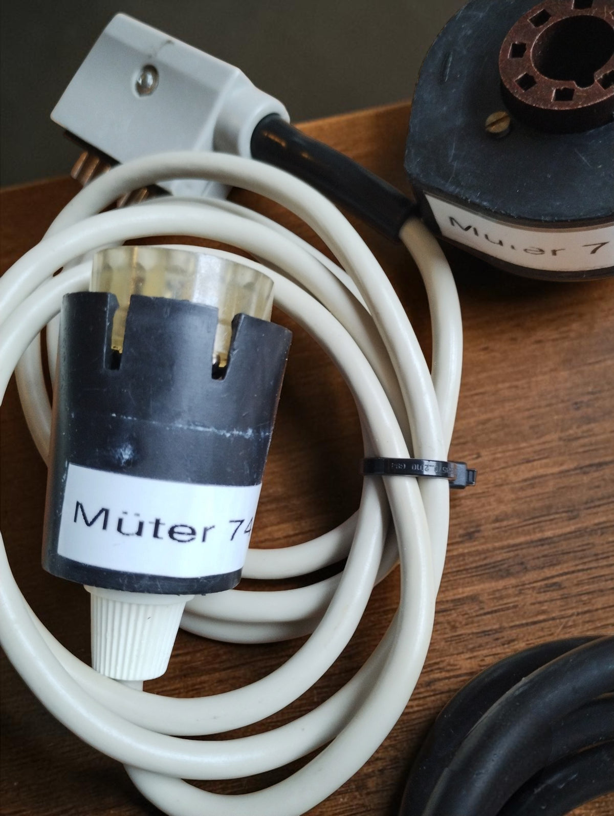 Close-up of a Müter CRT test adapter with coiled white connection cable and multipin plug
