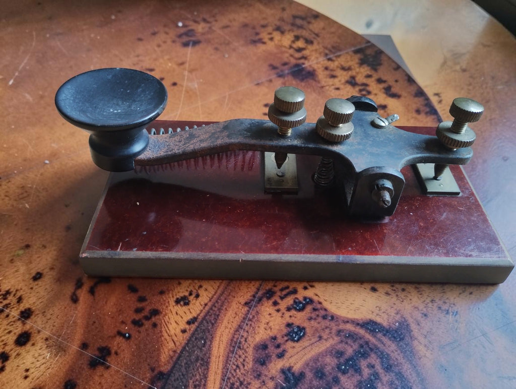 Opposite side of the antique Morse telegraph key, showing the metal lever, dished black knob and contact adjustment screws.
