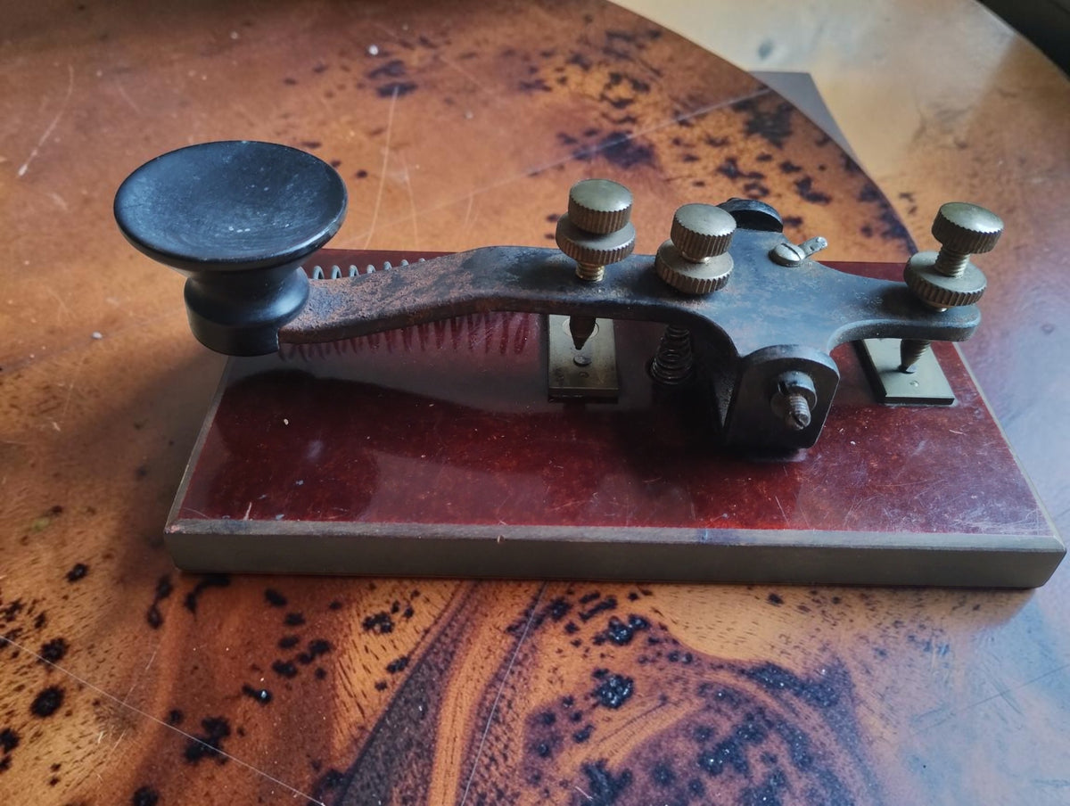 Opposite side of the antique Morse telegraph key, showing the metal lever, dished black knob and contact adjustment screws.
