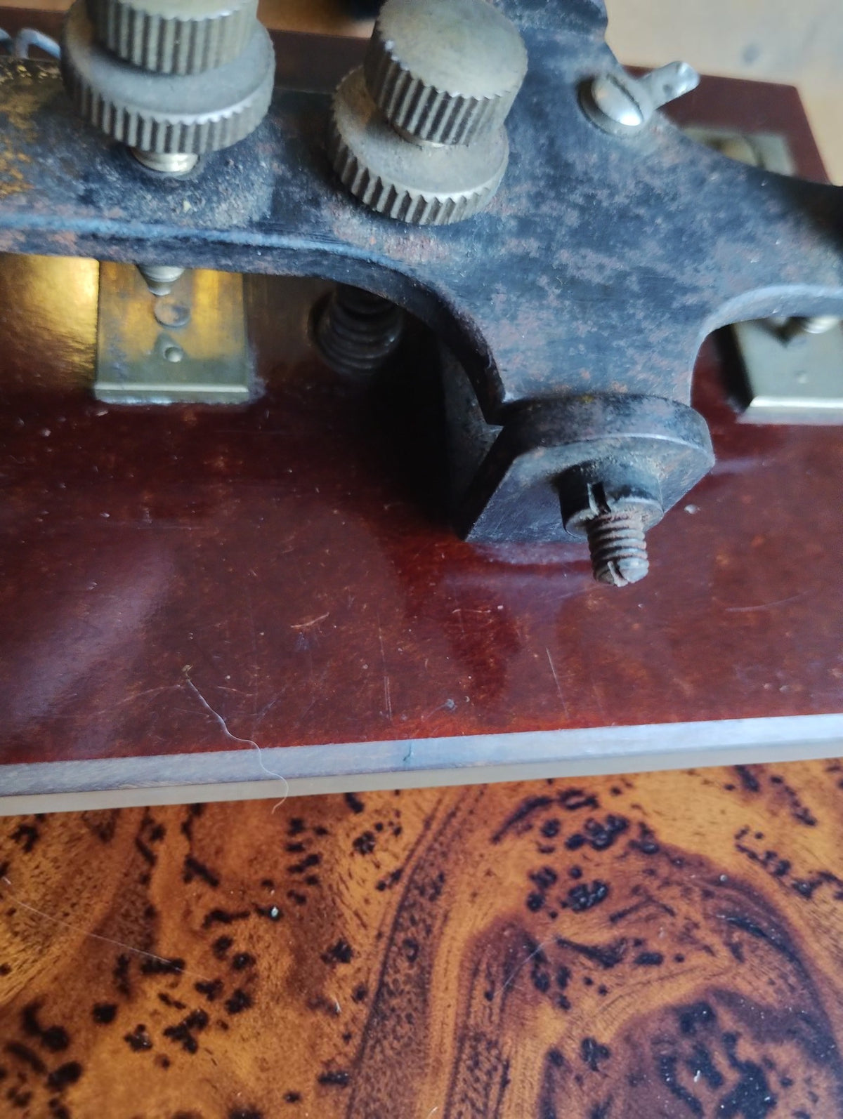 Close-up of the Morse telegraph key's pivot, knurled adjustment screws and contact mechanism, showing aged surface patina.
