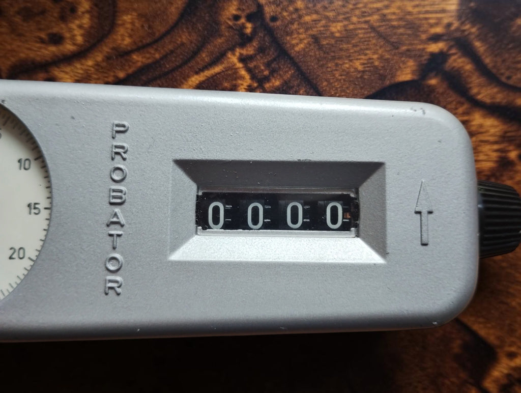 Close-up of the IVO Probator mechanical revolution counter showing four zero digits and the side knob
